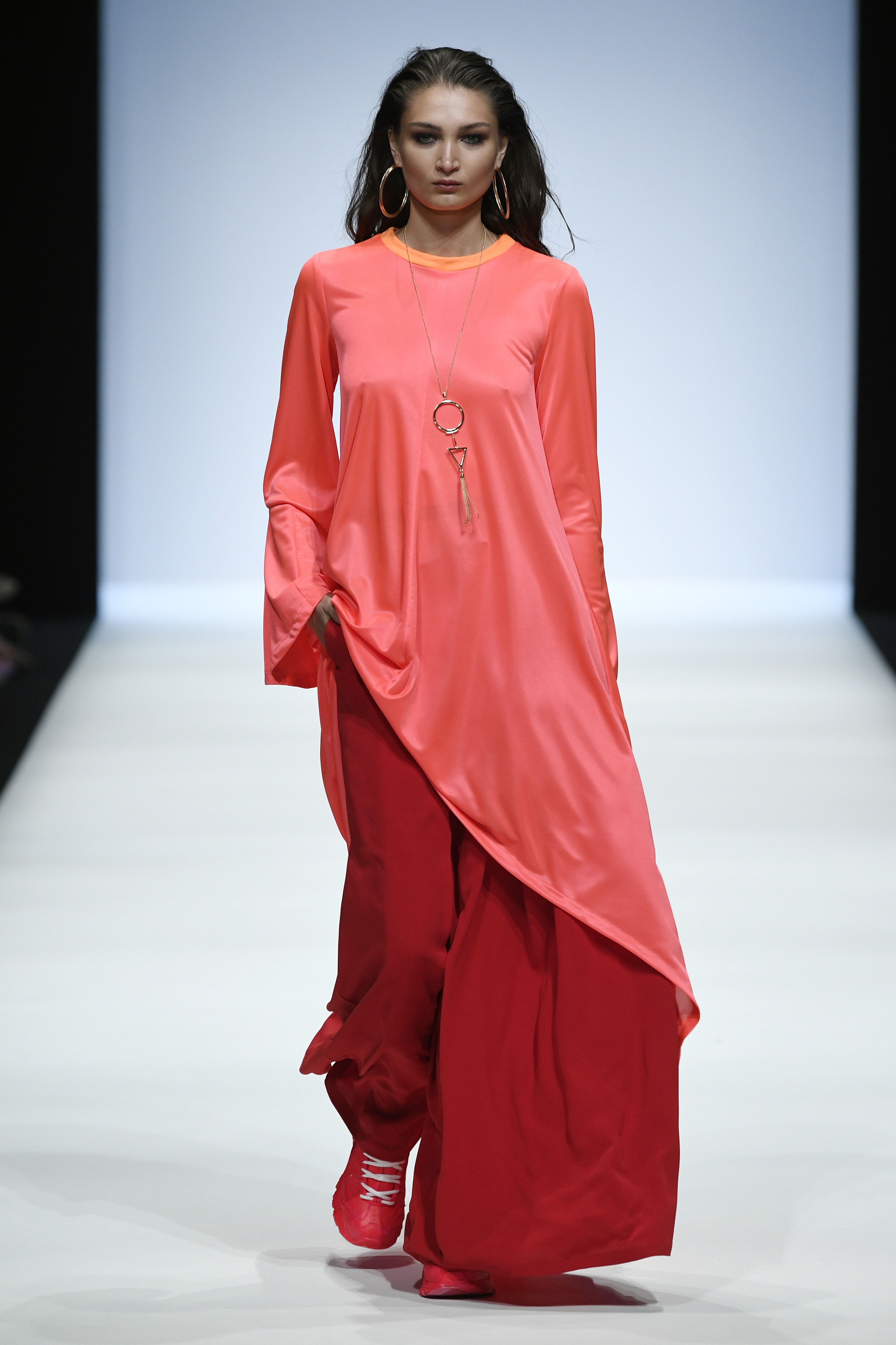XL-Creolen und eine goldfarbene Kette im Grafikdesign komplettieren das extravagante, asymmetrische Oversized-Dress auf dem Catwalk der Fashion Week