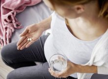 Frau mit Tabletten und Wasserglas