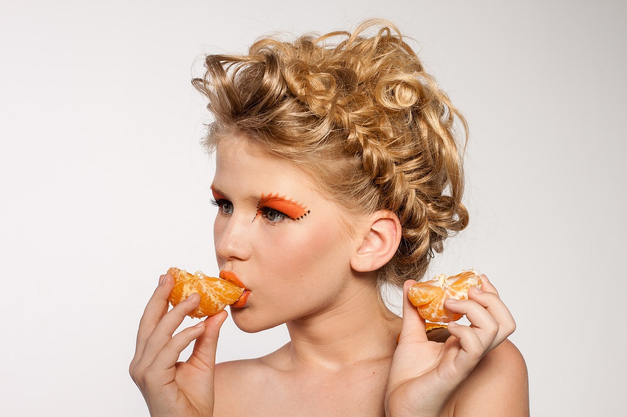 Orange geschminkte Frau isst Orange