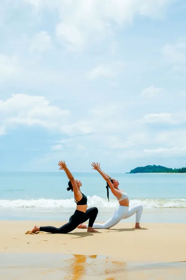 Zwei Frauen praktizieren Yoga am Strand