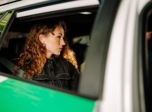 Frau sitzt im Auto, Blick durch die Seitenscheibe