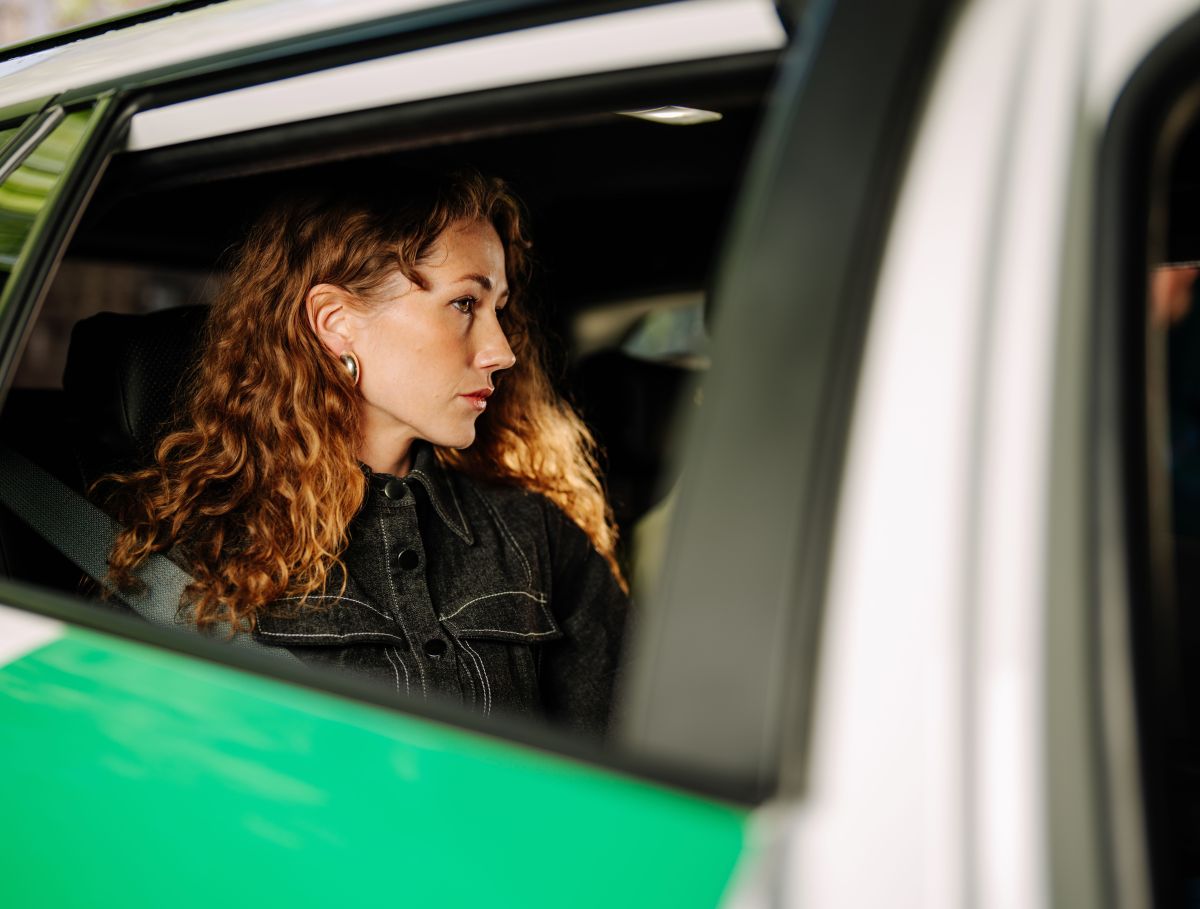 Frau sitzt im Auto, Blick durch die Seitenscheibe
