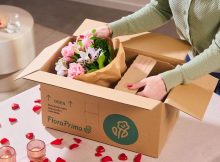 Frau öffnet Karton mit Blumengeschenk