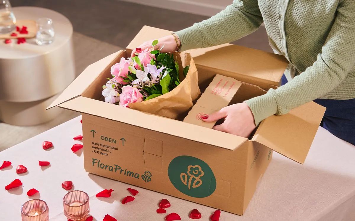 Frau &ouml;ffnet Karton mit Blumengeschenk