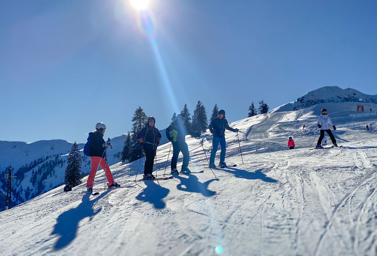 Gruppe junger Skifahrer am Hang in der Wintersonne