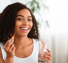 Junge farbige Frau mit einem Glas Wasser und Interdentalbürste