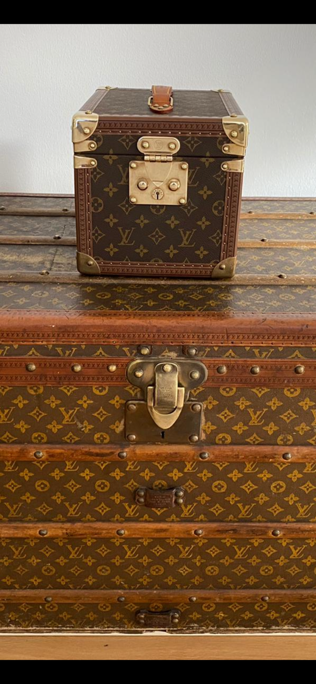Stacked Louis Vuitton suitcases: a small brown monogram box atop a larger matching trunk with brass hardware.